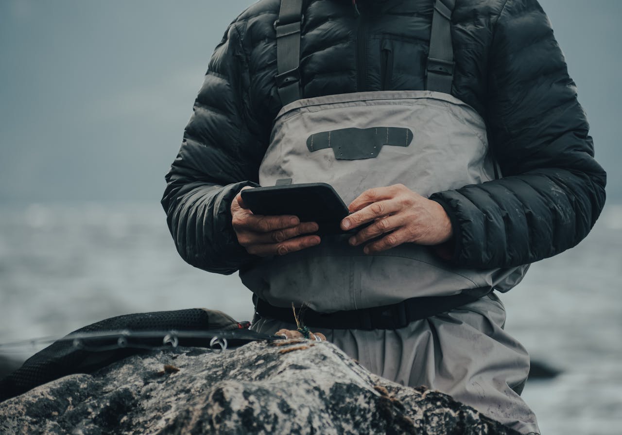 Man in protective clothing using tablet with gloves in cold, misty outdoor setting. Ideal for tech and outdoor adventure themes.